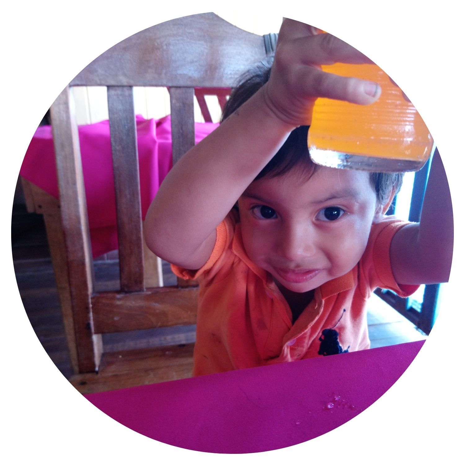 Un petit garçon en Nicaragua tient une bouteille de jus à la main, souriant et plein de joie. La scène capture un moment authentique de la vie quotidienne locale.