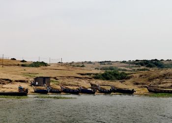 Paysage fluvial paisible en Ouganda avec des bateaux en bois amarrés le long de la rive sablonneuse, reflétant l’esprit d’aventure et la découverte tranquille