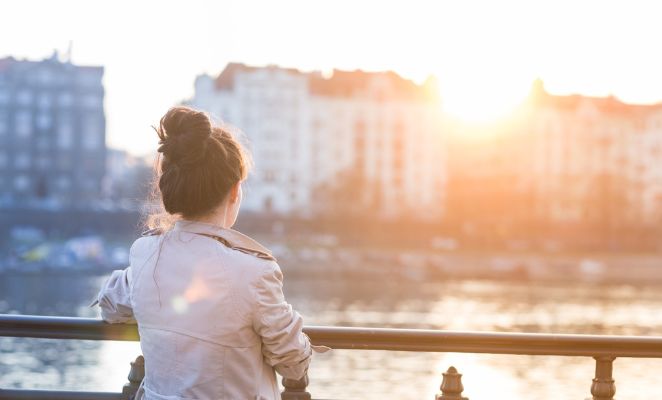 Une femme admire les silhouettes des bâtiments de Prague au coucher du soleil