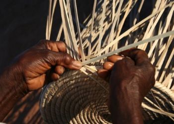 Artisan tanzanien tressant une corbeille en feuilles de palmier