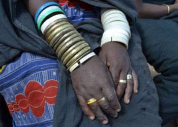 Mains d'une femme tanzanienne portant des bracelets traditionnels colorés.