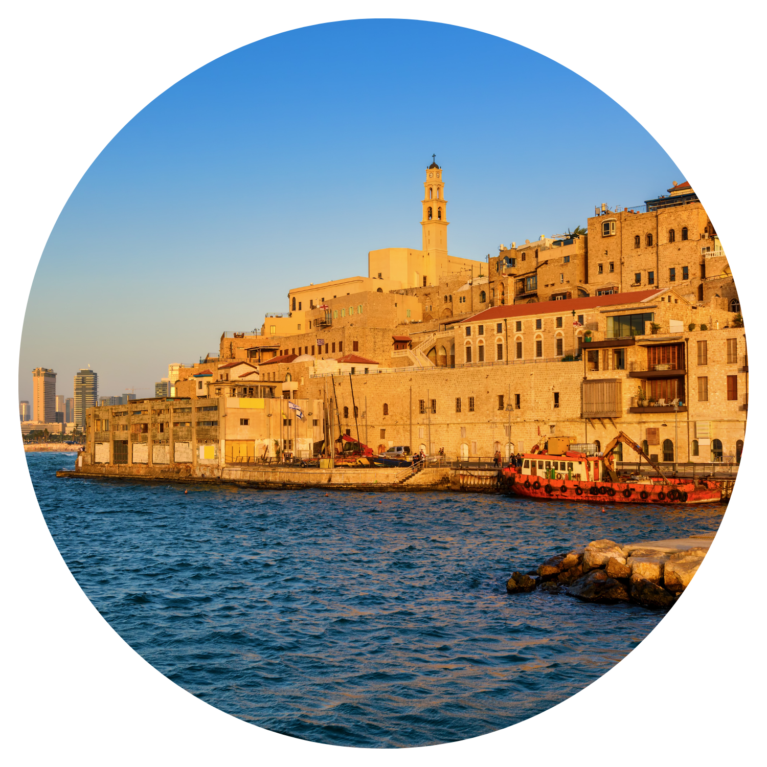 Le port de Jaffa en Israël capturé au coucher du soleil avec un reflet orange sur l'eau, teintant les maisons autour du port et un bateau amarré au quai.
