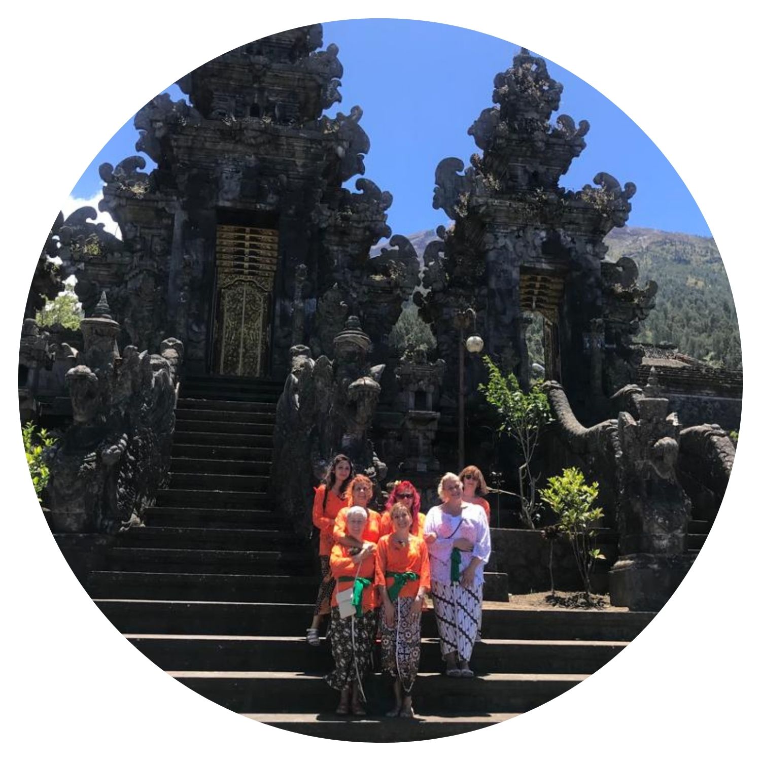 Groupe de femmes vêtues de tenues traditionnelles balinaises, prenant une photo de groupe devant un monument après une visite enrichissante.