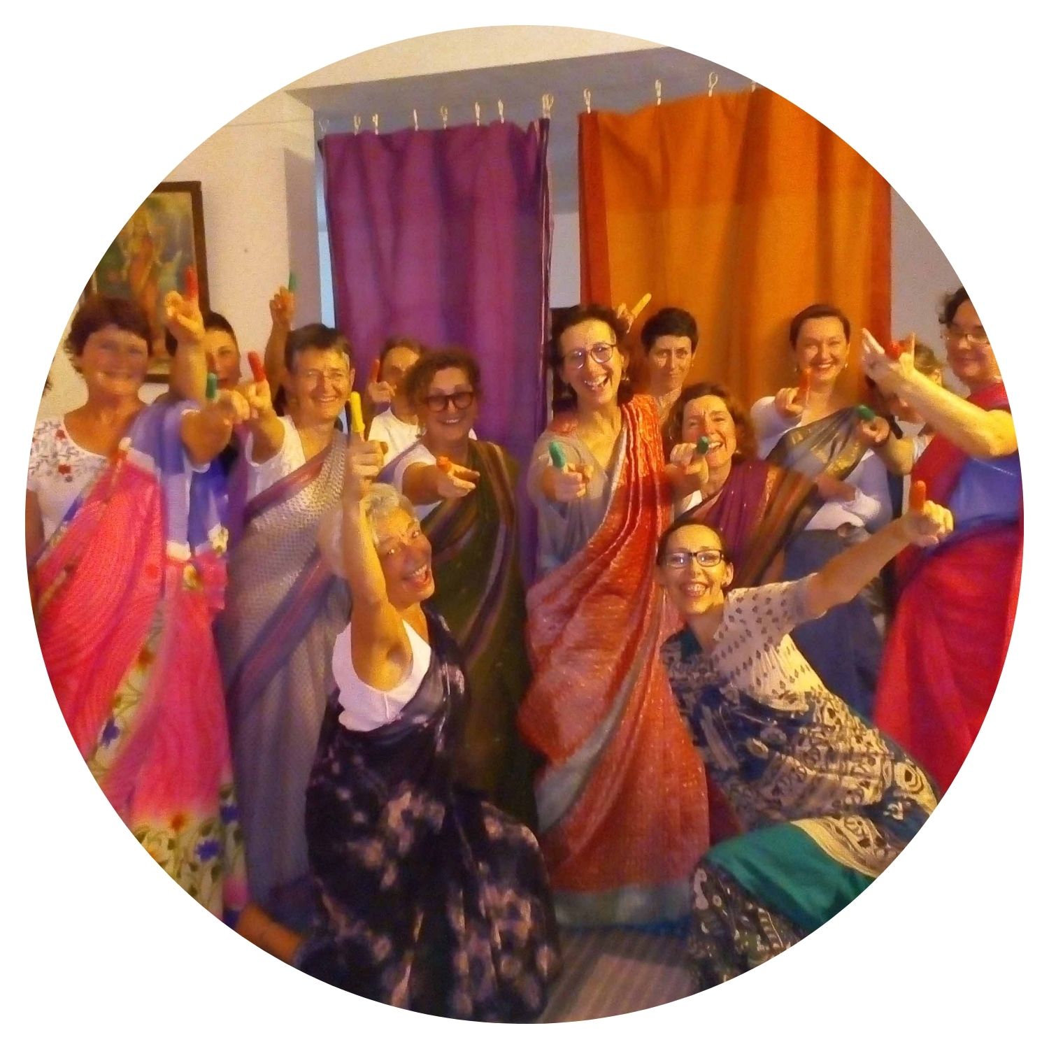 Un groupe de femmes souriantes essaie des tenues traditionnelles indiennes colorées, capturant l'essence de leur voyage culturel en Inde.