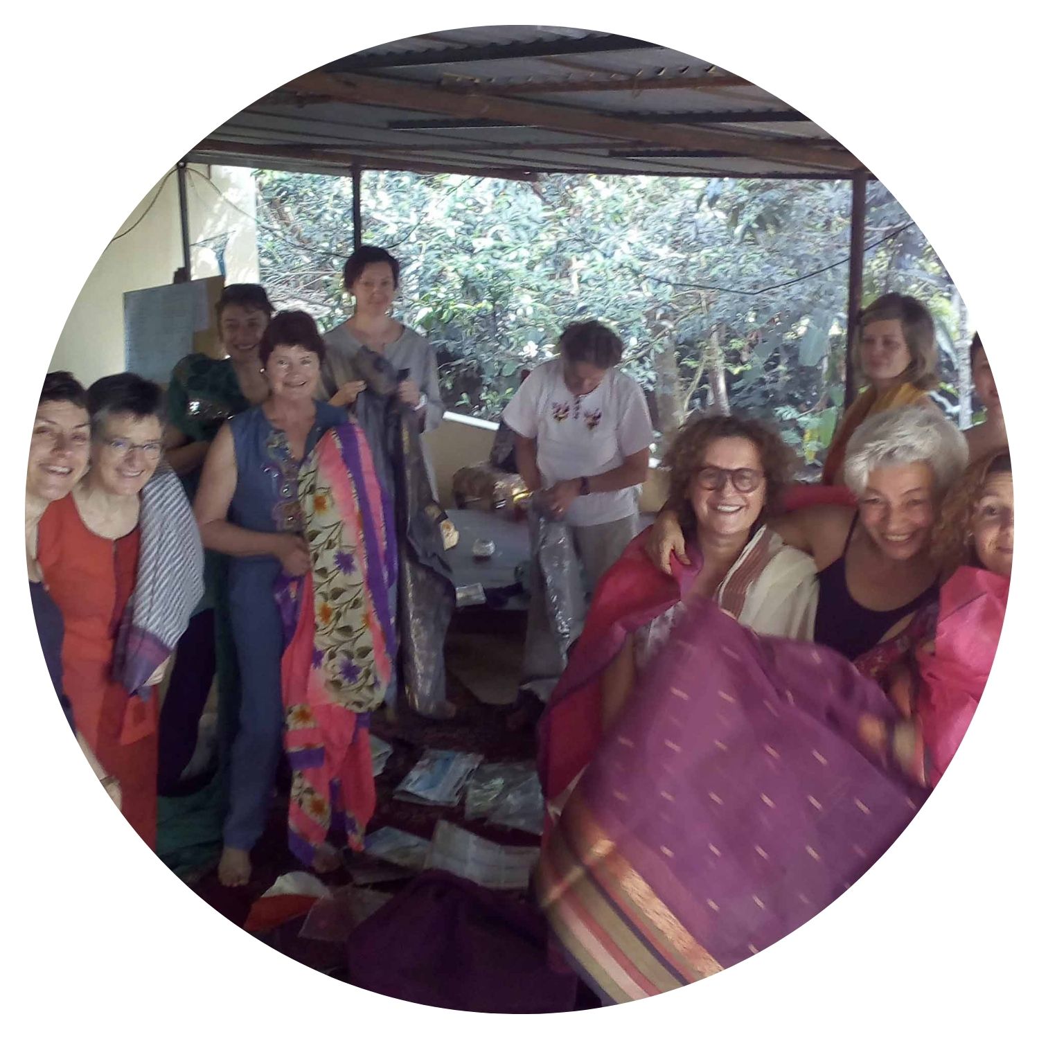 Un groupe de femmes souriantes essaie des tenues traditionnelles indiennes colorées, capturant l'essence de leur voyage culturel en Inde.