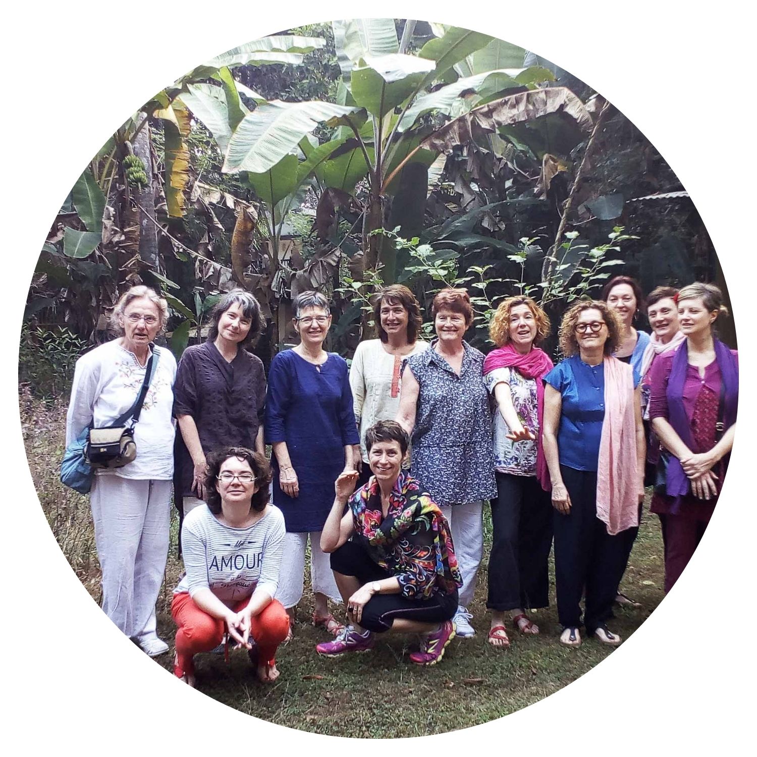 Un groupe de femmes souriantes pose pour une photo après avoir exploré une forêt sauvage en Inde, avec la verdure luxuriante en arrière-plan.